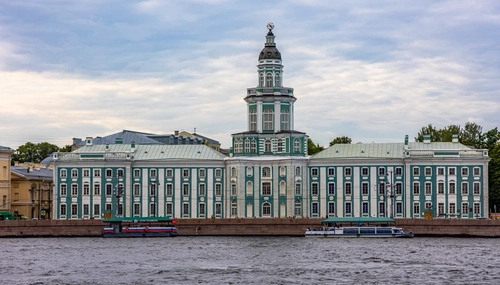 Кунсткамера, зелёно-белое здание с центральной башней на набережной; по реке идут прогулочные катера
