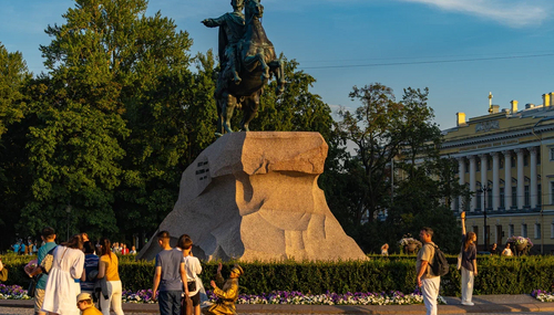 Конный памятник на гранитном постаменте в парке на Сенатской площади; люди гуляют у цветников